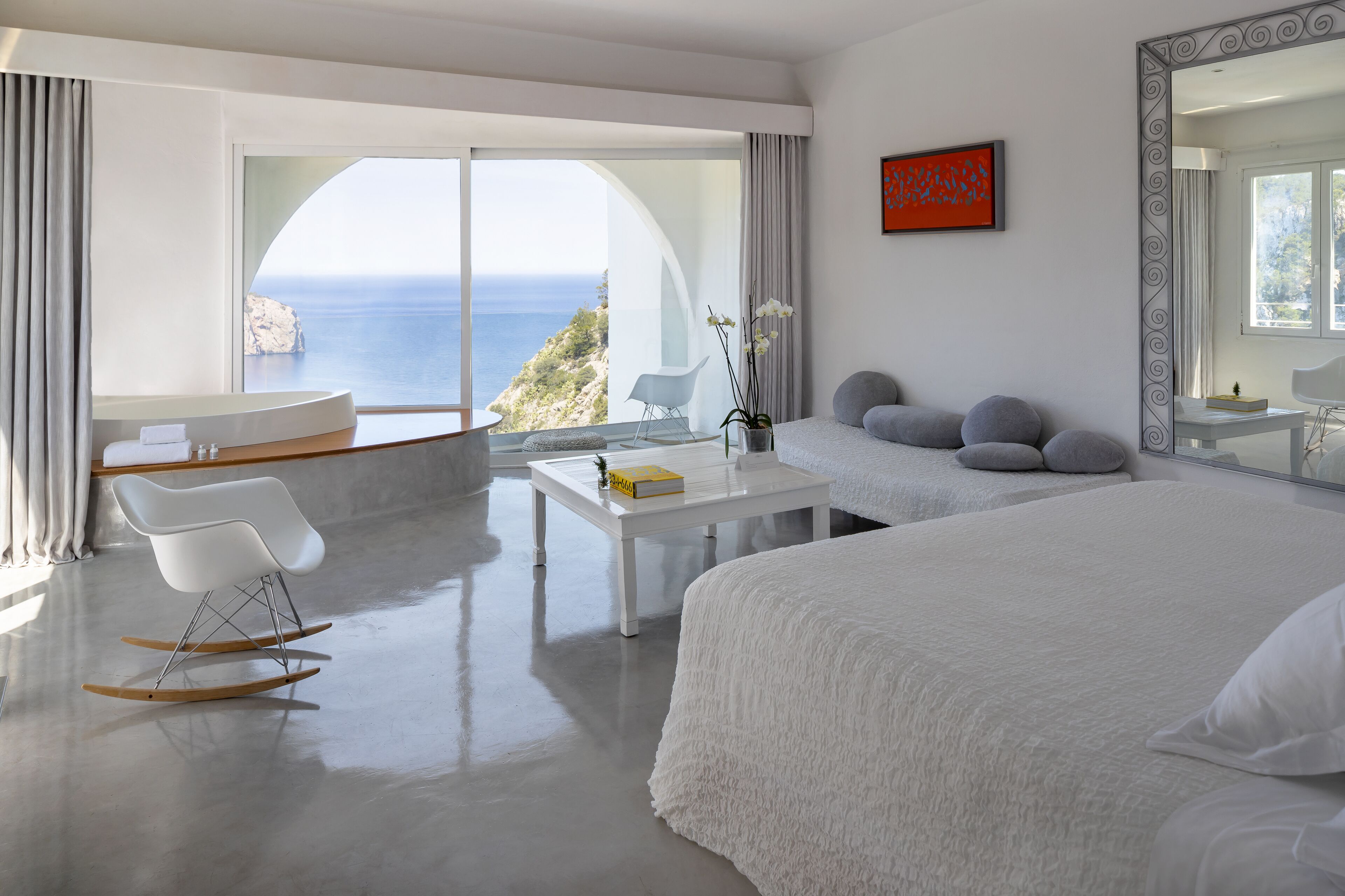 Une chambre moderne avec un grand lit, un bureau blanc et une vue sur la mer.