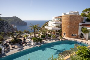 Un complexe hôtelier doté d’une grande piscine, de palmiers et offrant une vue sur la mer.