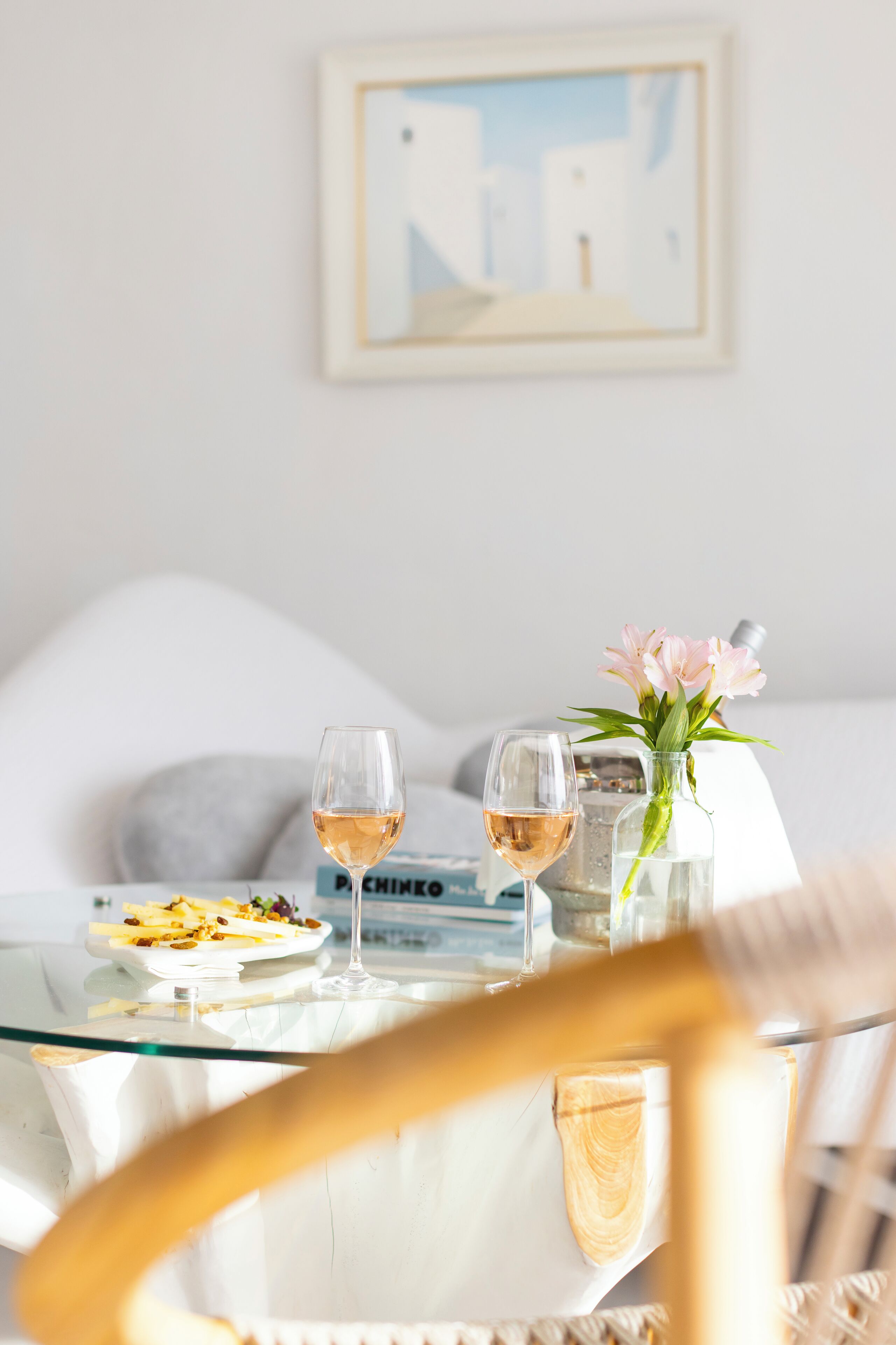 Une table à manger avec deux verres à vin, un vase de fleurs et une assiette de nourriture.