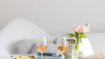 Une table à manger avec deux verres à vin, un vase de fleurs et une assiette de nourriture.