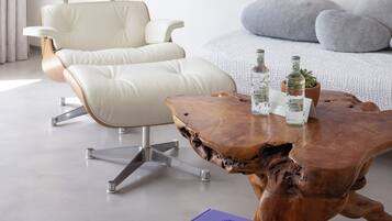 Un moderno salón con un sillón de cuero blanco, una mesa de centro de madera con un libro y un gran cuadro abstracto en la pared.