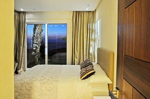A hotel room with a bed, a view of the outdoors, and a wooden door.