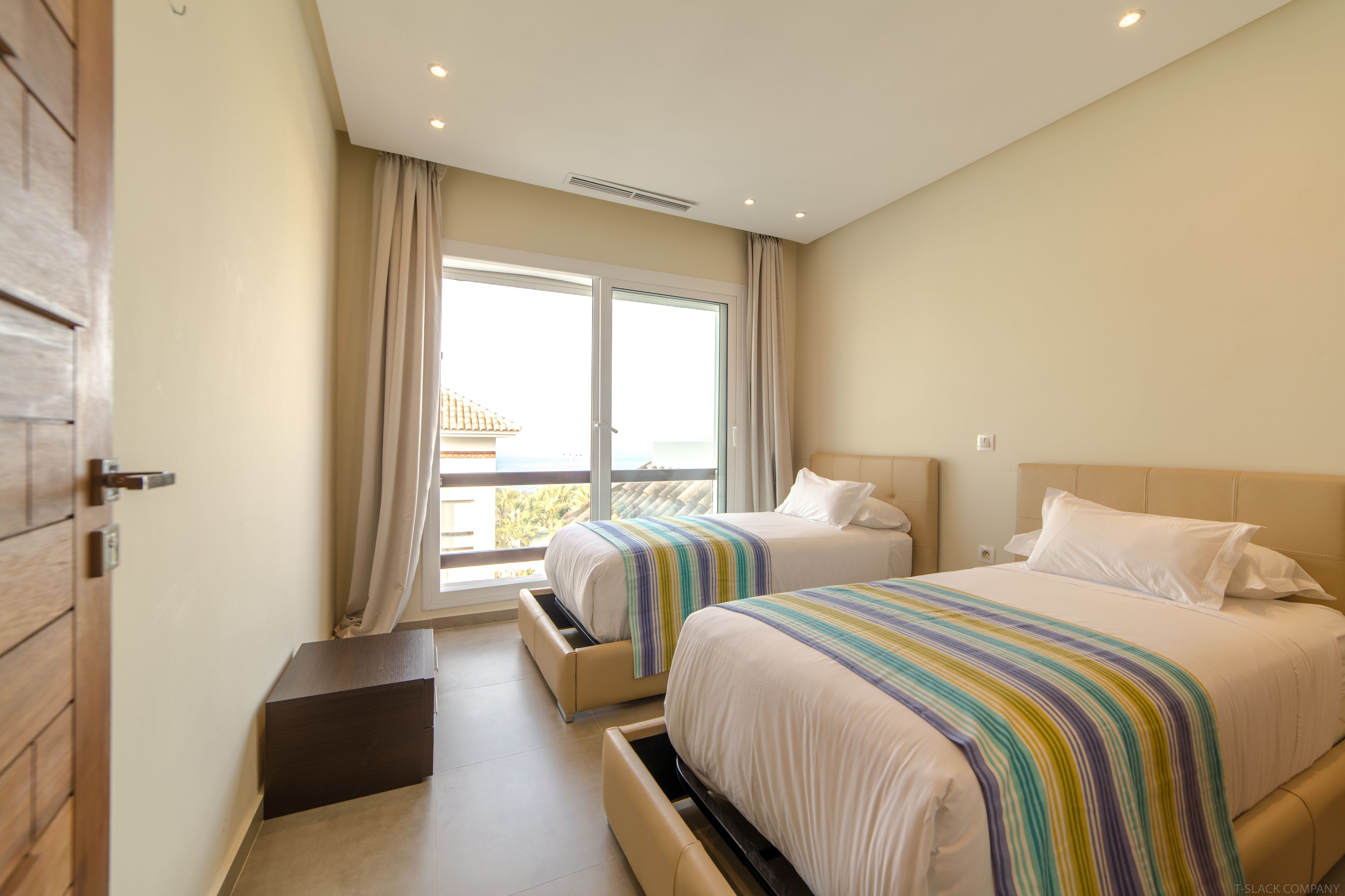 Ein Hotelzimmer mit zwei Betten, einer Schiebetür zum Balkon und einer kleinen Ablagebank.
