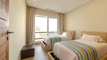 Ein Hotelzimmer mit zwei Betten, einer Schiebetür zum Balkon und einer kleinen Ablagebank.