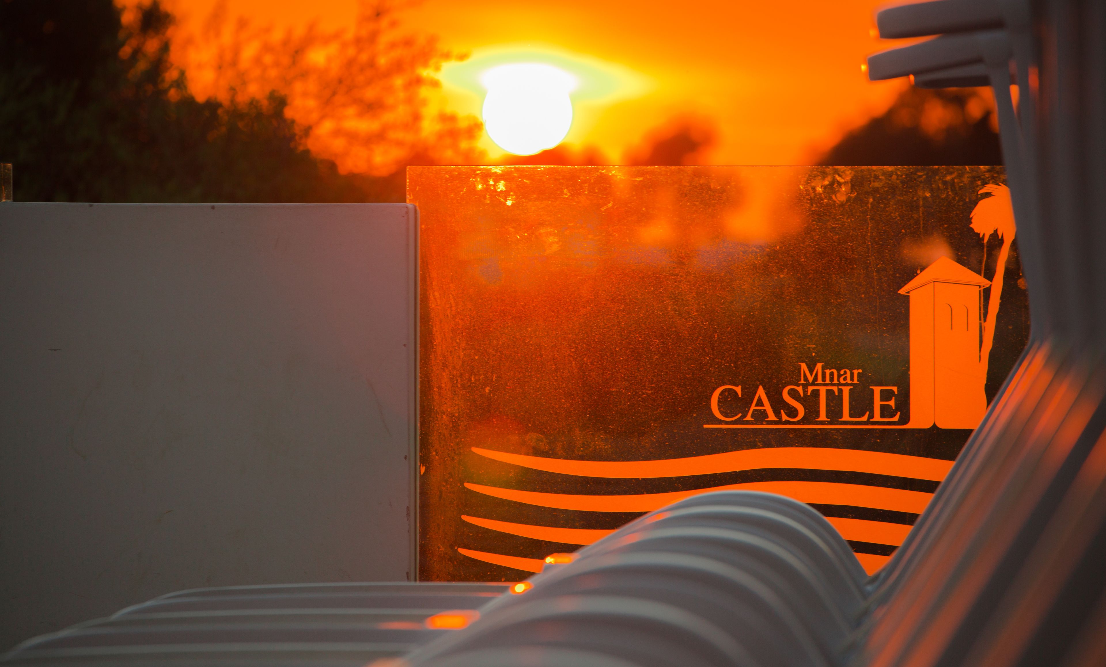 A sunset view with a sign reading "Mnar CASTLE" in the background.