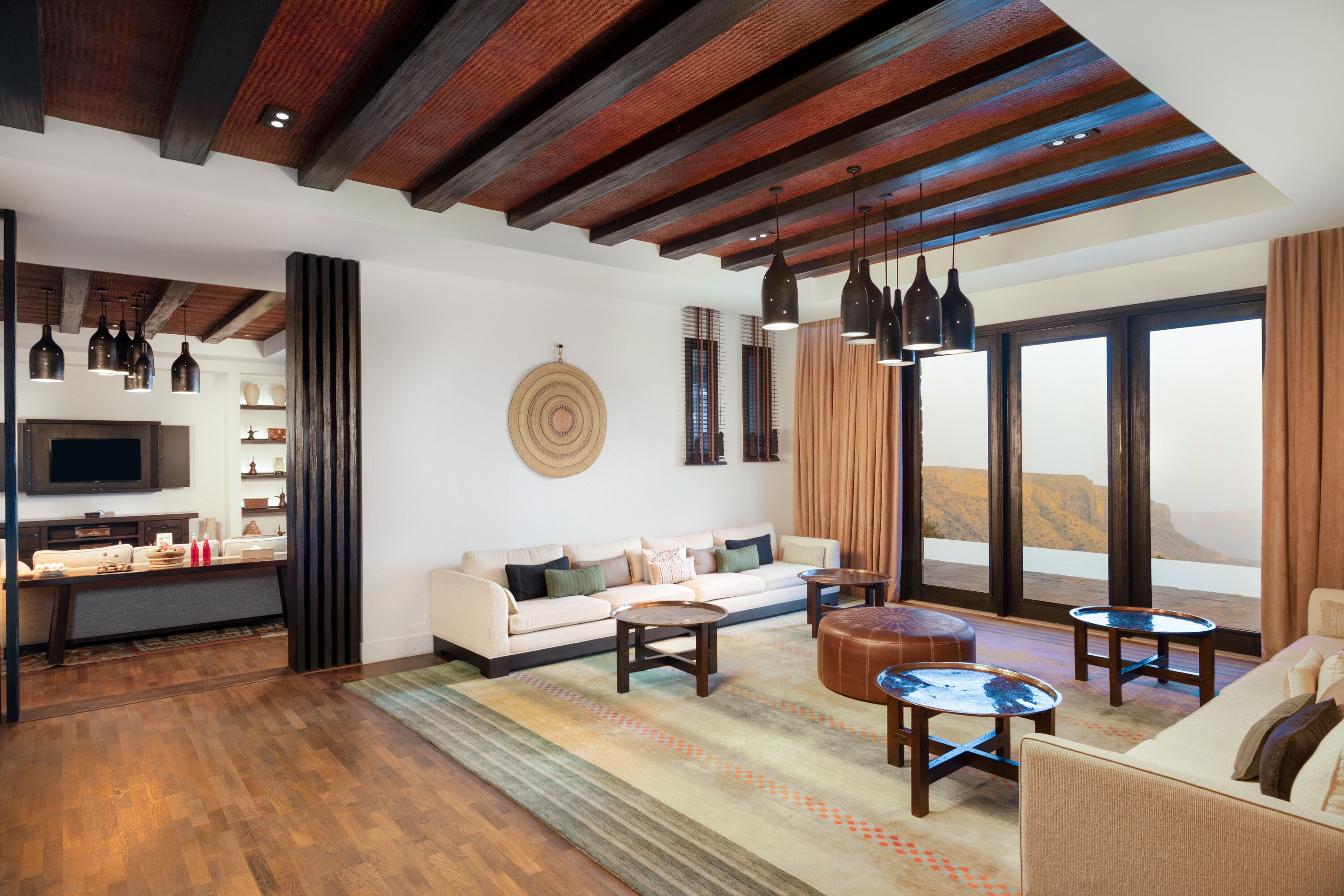 A modern living room with a wooden ceiling, a sofa, two coffee tables, and a TV on a stand.