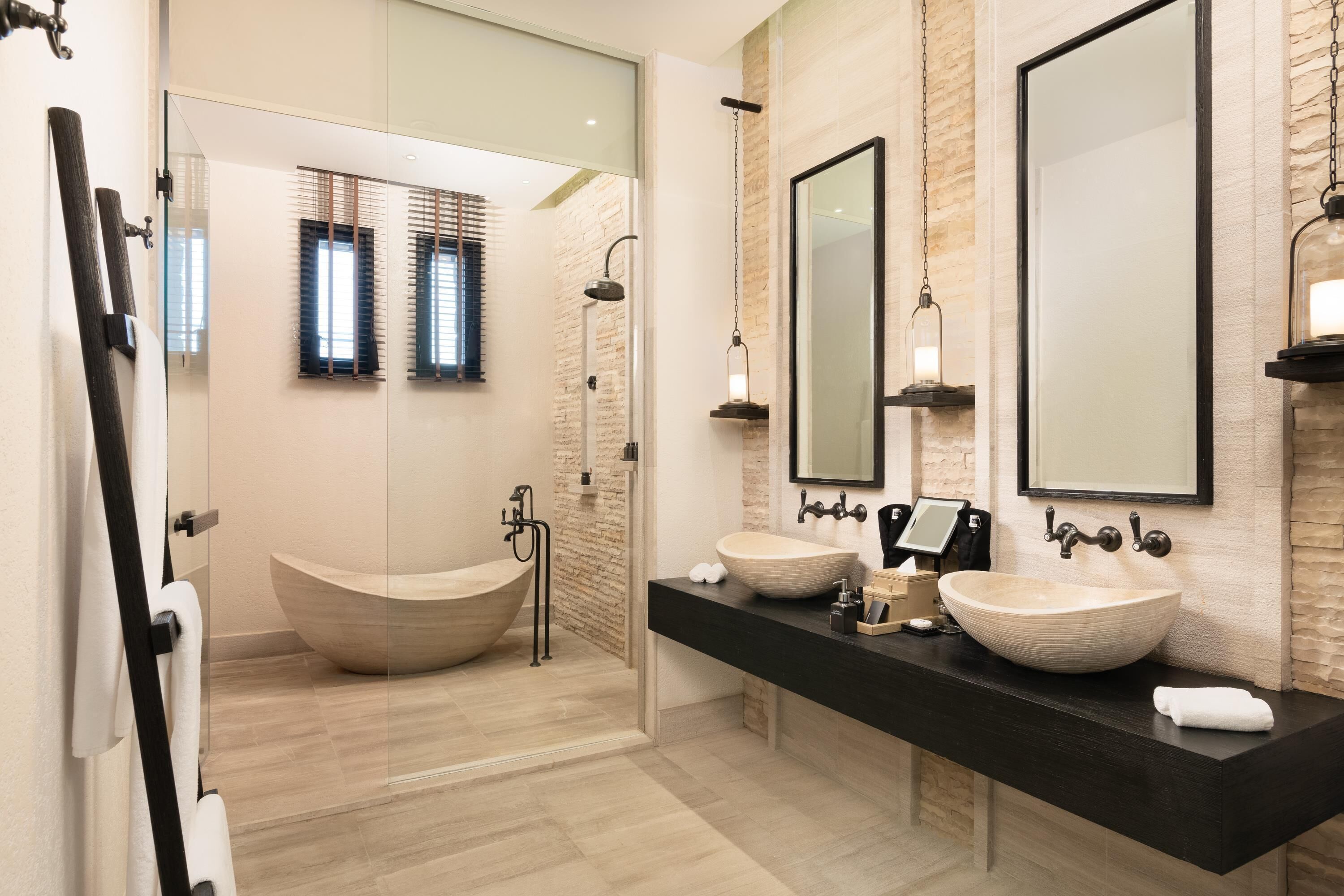 Une salle de bain moderne avec une baignoire sur pieds, un grand miroir et un plan de toilette noir doté de deux vasques.