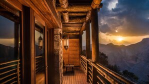 Un balcón de madera con vistas a un paisaje montañoso al atardecer.