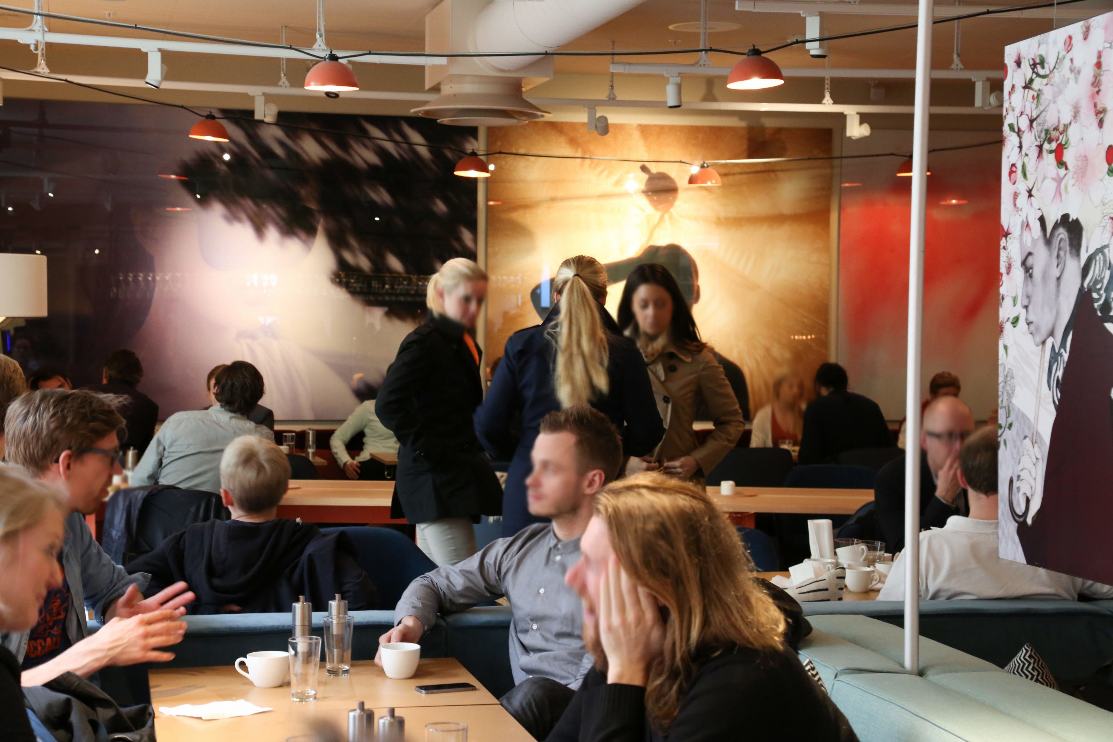 A busy indoor dining area with tables, chairs, and people engaged in conversation.