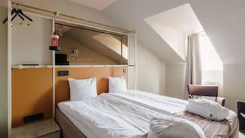 Una habitación de hotel con cama, una silla, un escritorio y un ventanal con cortinas.
