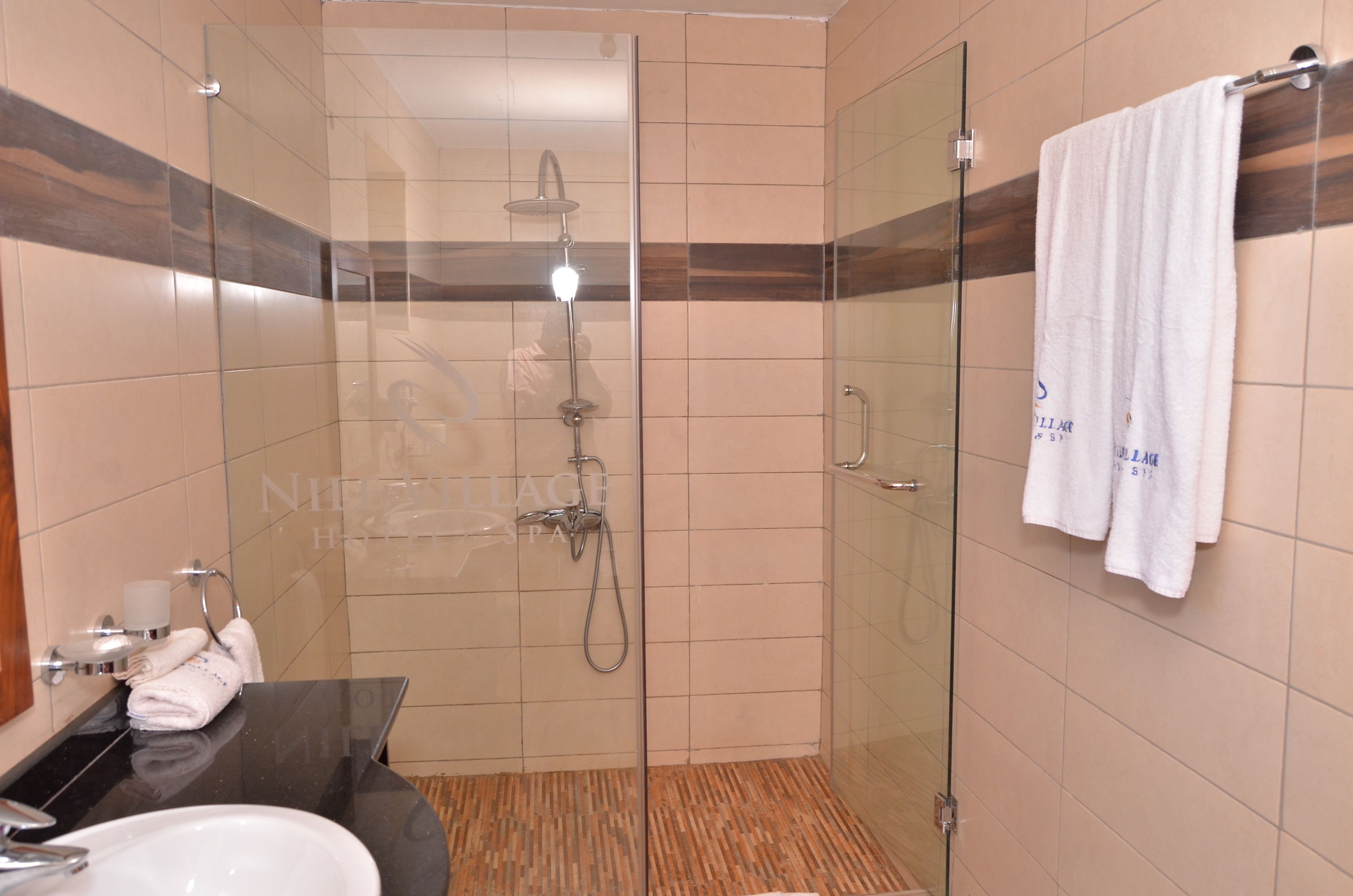 Un baño moderno con cabina de ducha acristalada, lavamanos de encimera negro y una toalla blanca colgada en la pared.