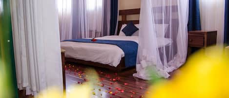 Una cama bien hecha con un edredón azul y una sola rosa encima.