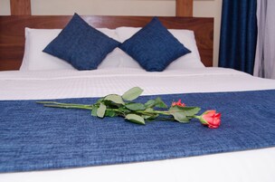Ein ordentlich bezogenes Bett mit einer blauen Tagesdecke und zwei blauen Kopfkissen.