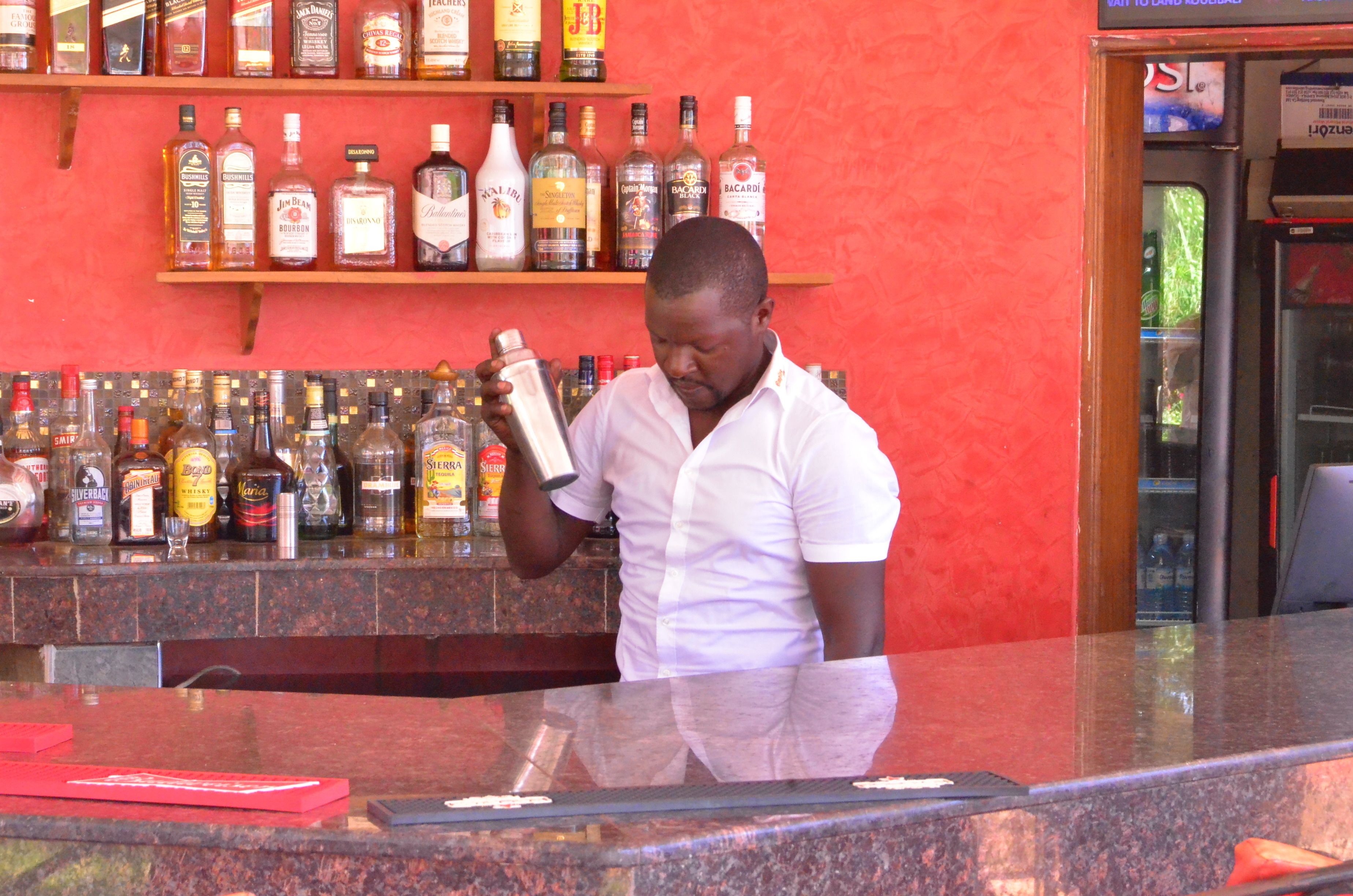 A bar with a variety of liquor bottles on shelves and a person holding a bottle.