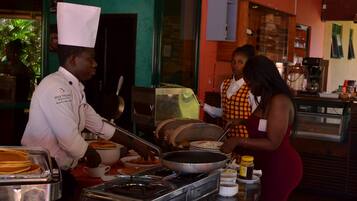 A buffet setup with various food items and a chef serving.