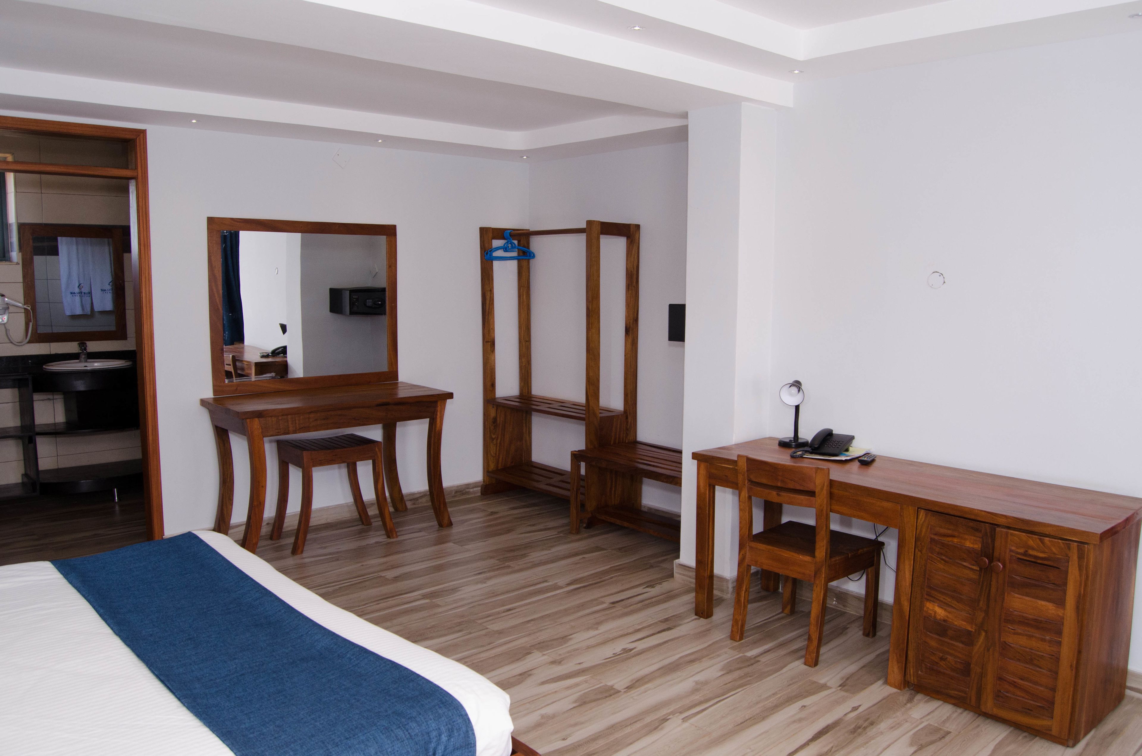 Ein Hotelzimmer mit einem Bett, Schreibtisch aus Holz, Stuhl und Spiegel.