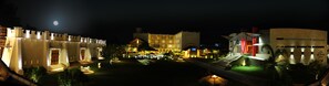 A nighttime view of a hotel courtyard with a pool, outdoor seating, and illuminated buildings. - Avenra Garden Hotel (Negombo)