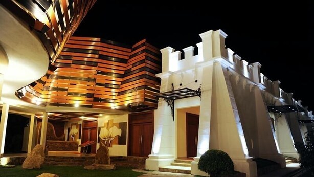 Un edificio moderno con un diseño arquitectónico único, que presenta una fachada curva y una estructura similar a un castillo con columnas blancas y una rampa que conduce a la entrada.