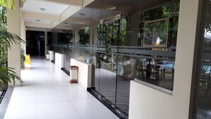 Un moderno hall de hotel con separador de vidrio, suelo de baldosas y plantas de interior.