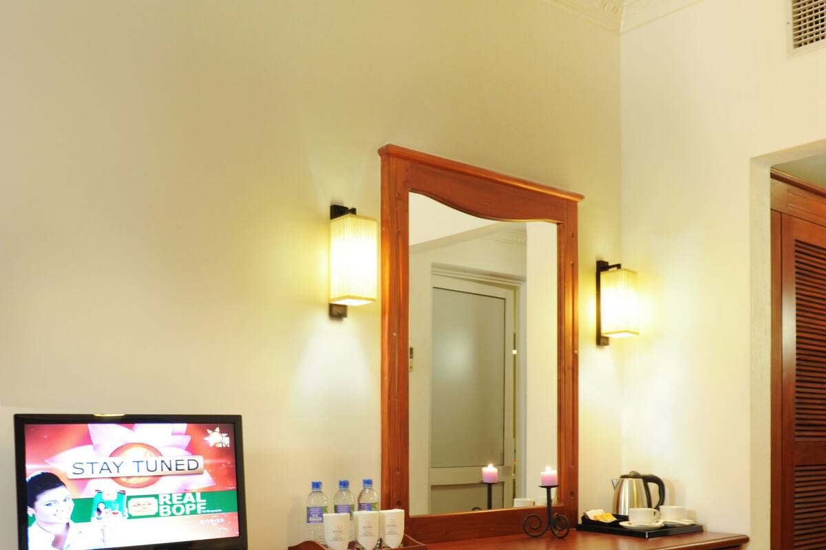 A wooden console with a TV, a mirror, and a small stool.