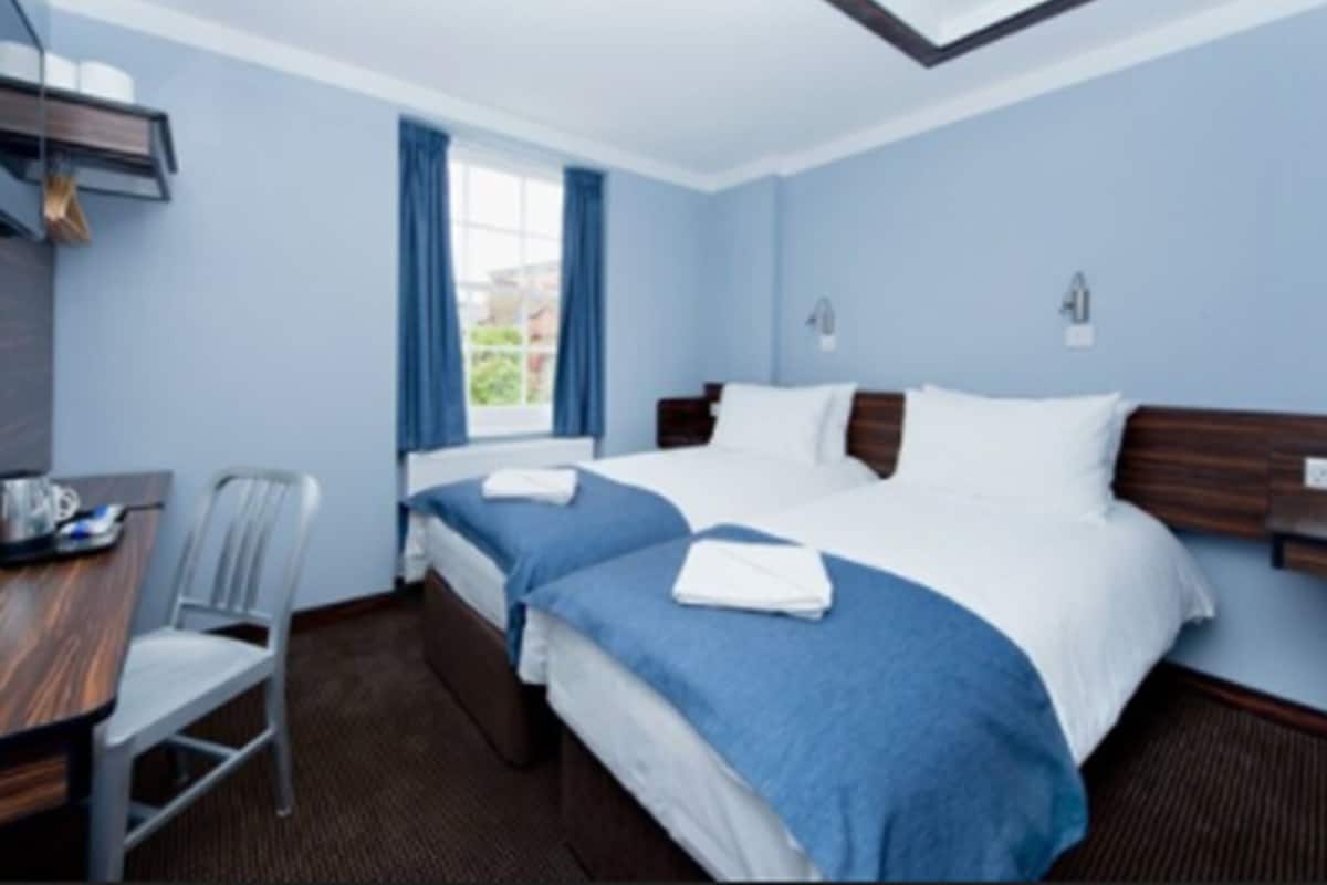 A hotel room with a large bed, a desk, and a chair.