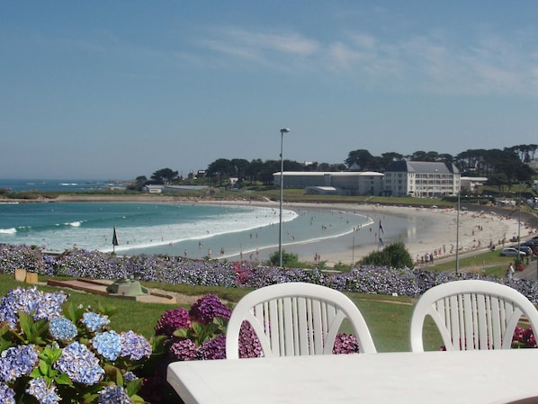 A beach with people, a building, and a chair in the foreground.
