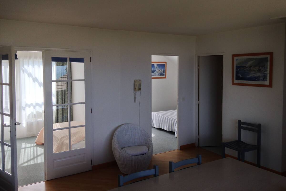 A room with a bed, a chair, a table, and a painting on the wall.
