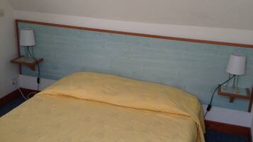 A bed with a patterned bedspread, a wooden headboard, and two bedside lamps on wooden nightstands.
