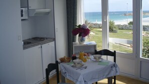 Ein Essbereich mit einem für das Frühstück gedeckten Tisch, Blick auf den Ozean und einer Küchenzeile.