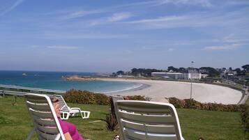 Une plage avec vue sur la mer, des chaises longues et une personne se relaxant.