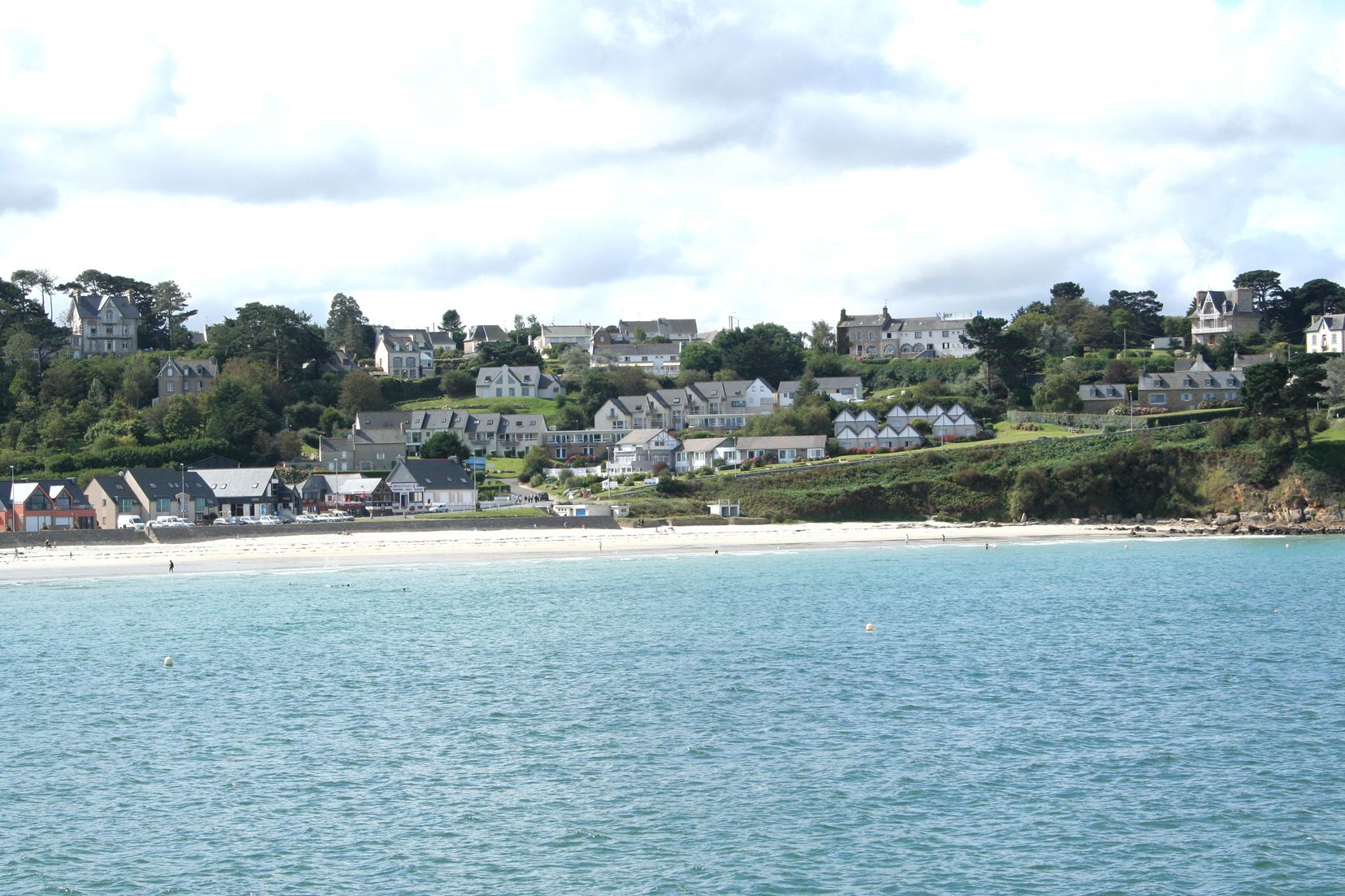 A coastal town with houses on a hillside overlooking a beach.