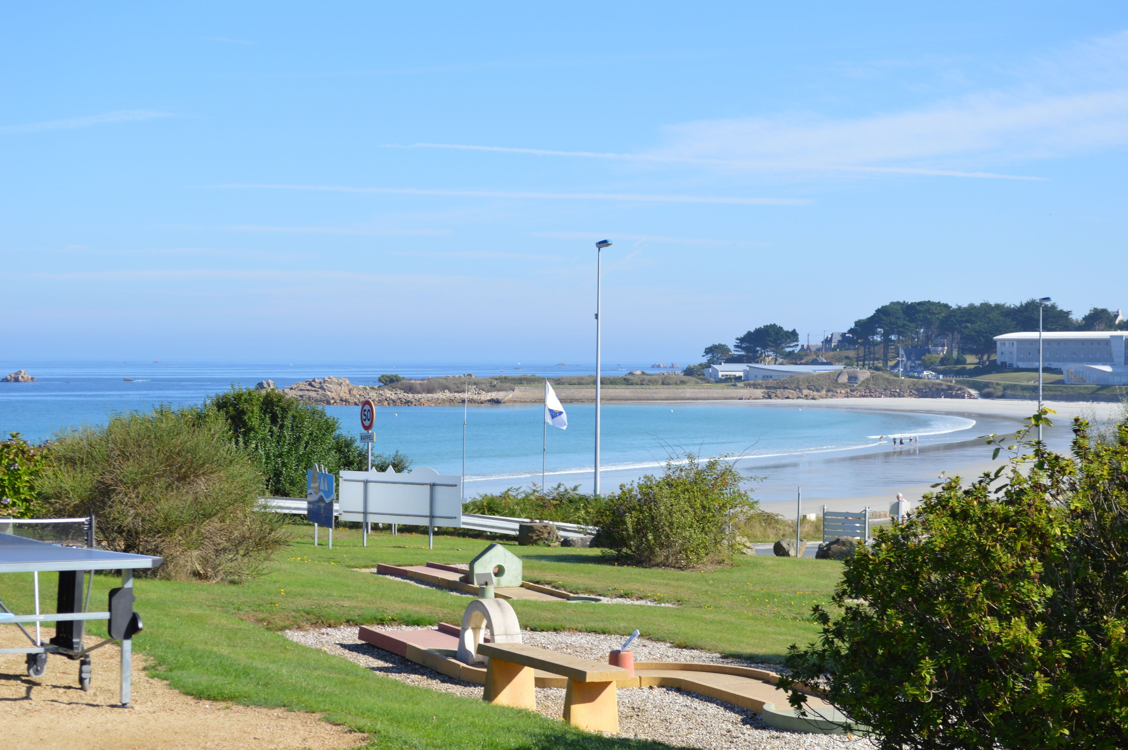 A coastal view with a beach, a flag, and a tennis court.