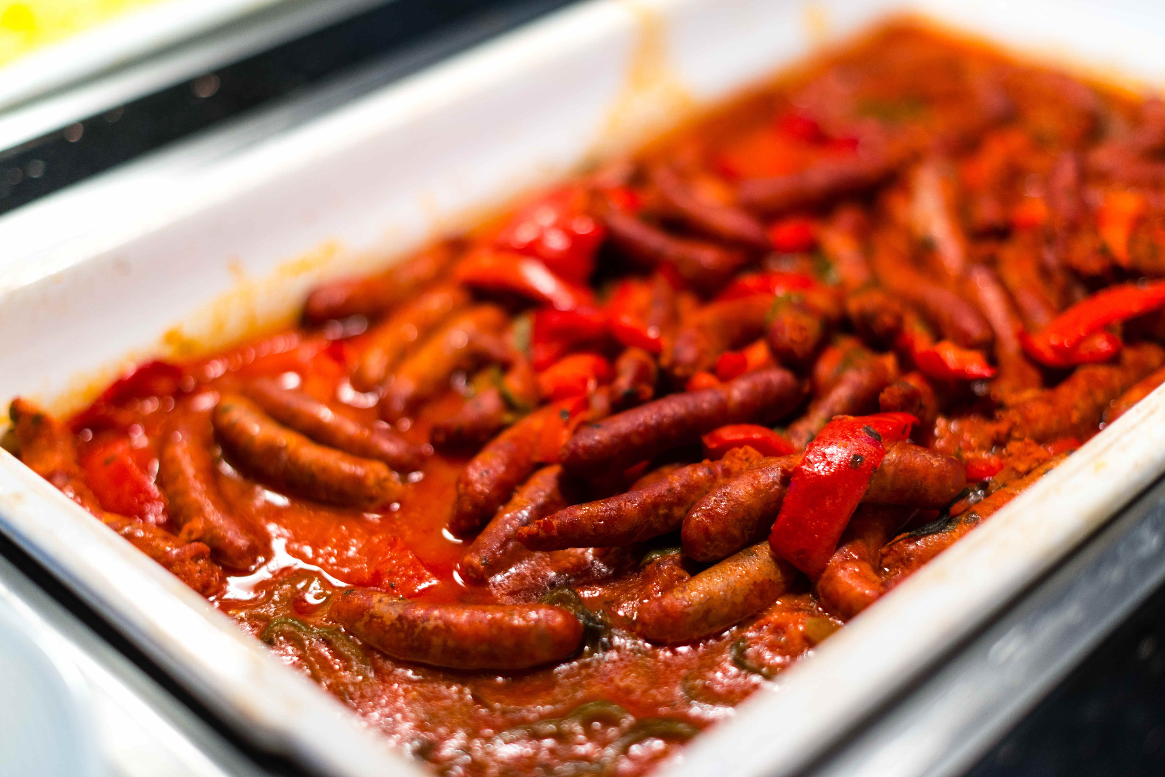 Un plato de salchichas en salsa roja con pimientos rojos.