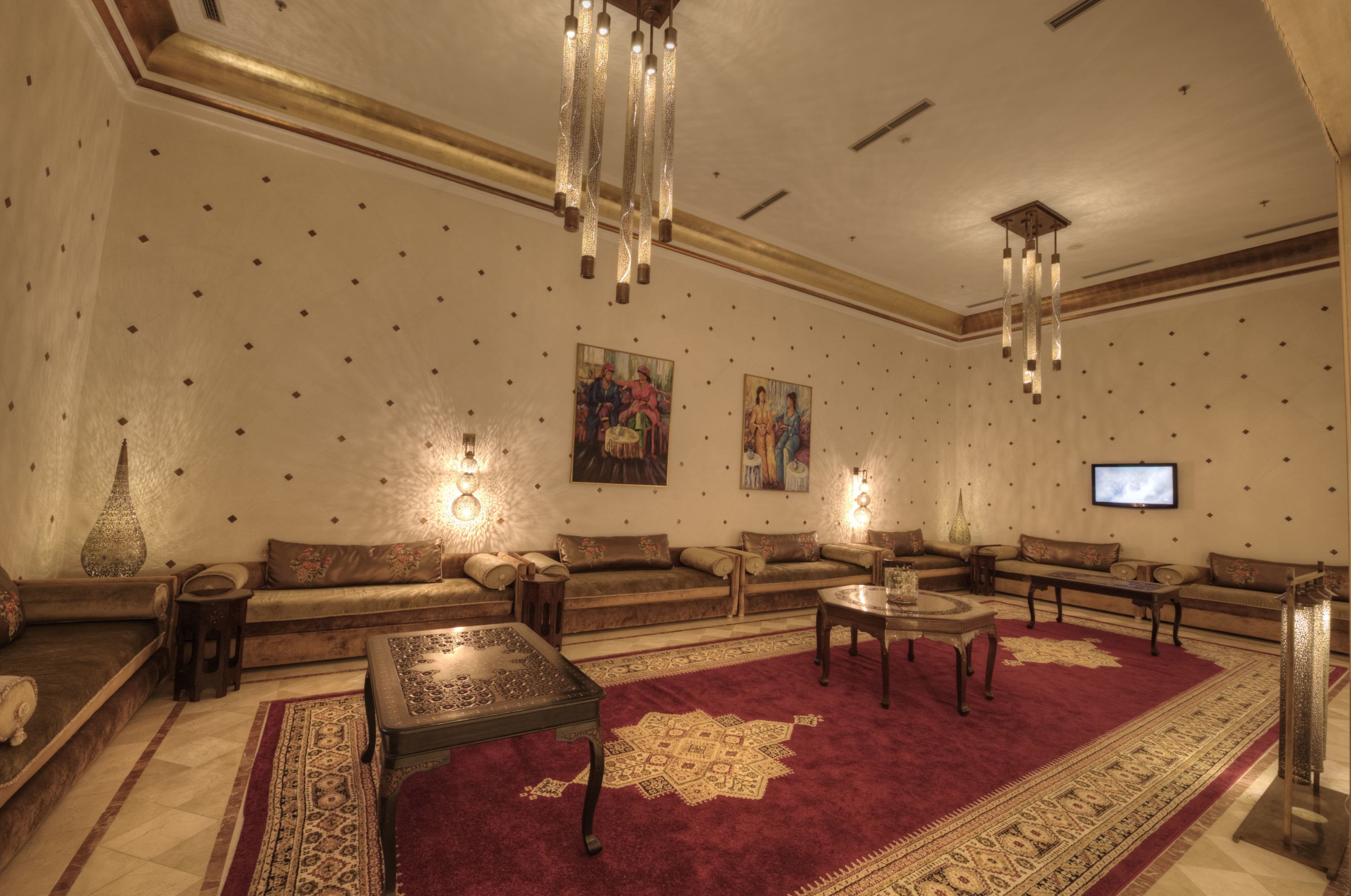 A spacious living room with a red carpet, multiple sofas, a coffee table, and wall-mounted lighting.