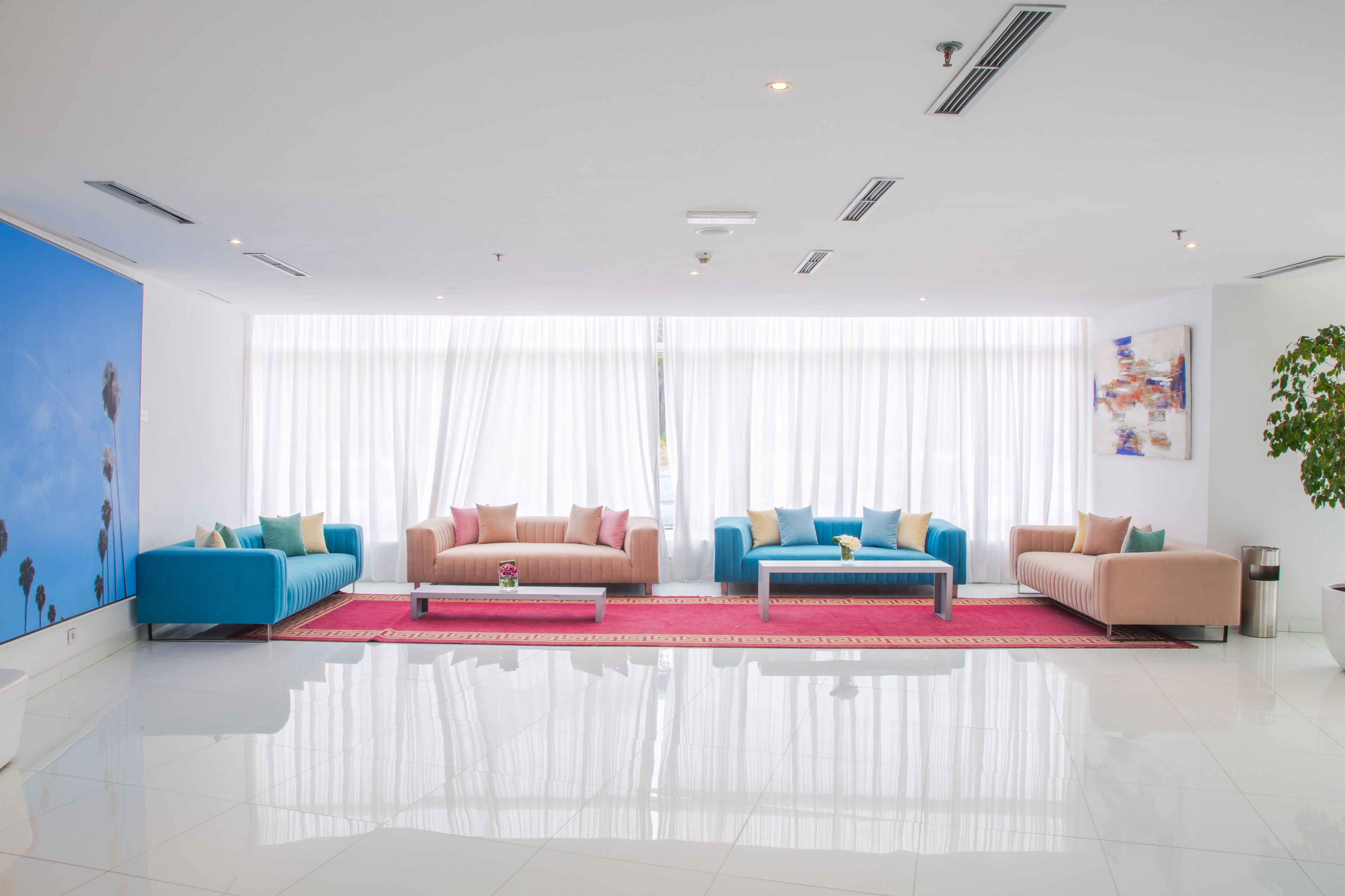 Una sala de estar moderna con dos sofás, una mesita de centro y un ventanal con cortinas traslúcidas.