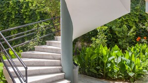 A staircase with metal railings leading to a landing, surrounded by lush greenery and plants. - Akasti Hotel (Chania)