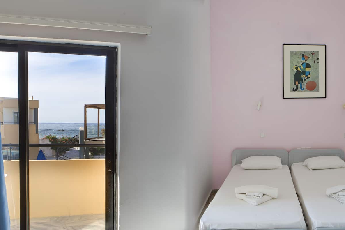 Una habitación con dos camas, una pared rosa y un cuadro enmarcado.