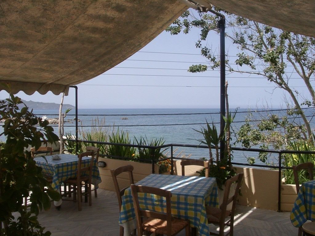 An outdoor seating area with tables and chairs, overlooking a body of water.