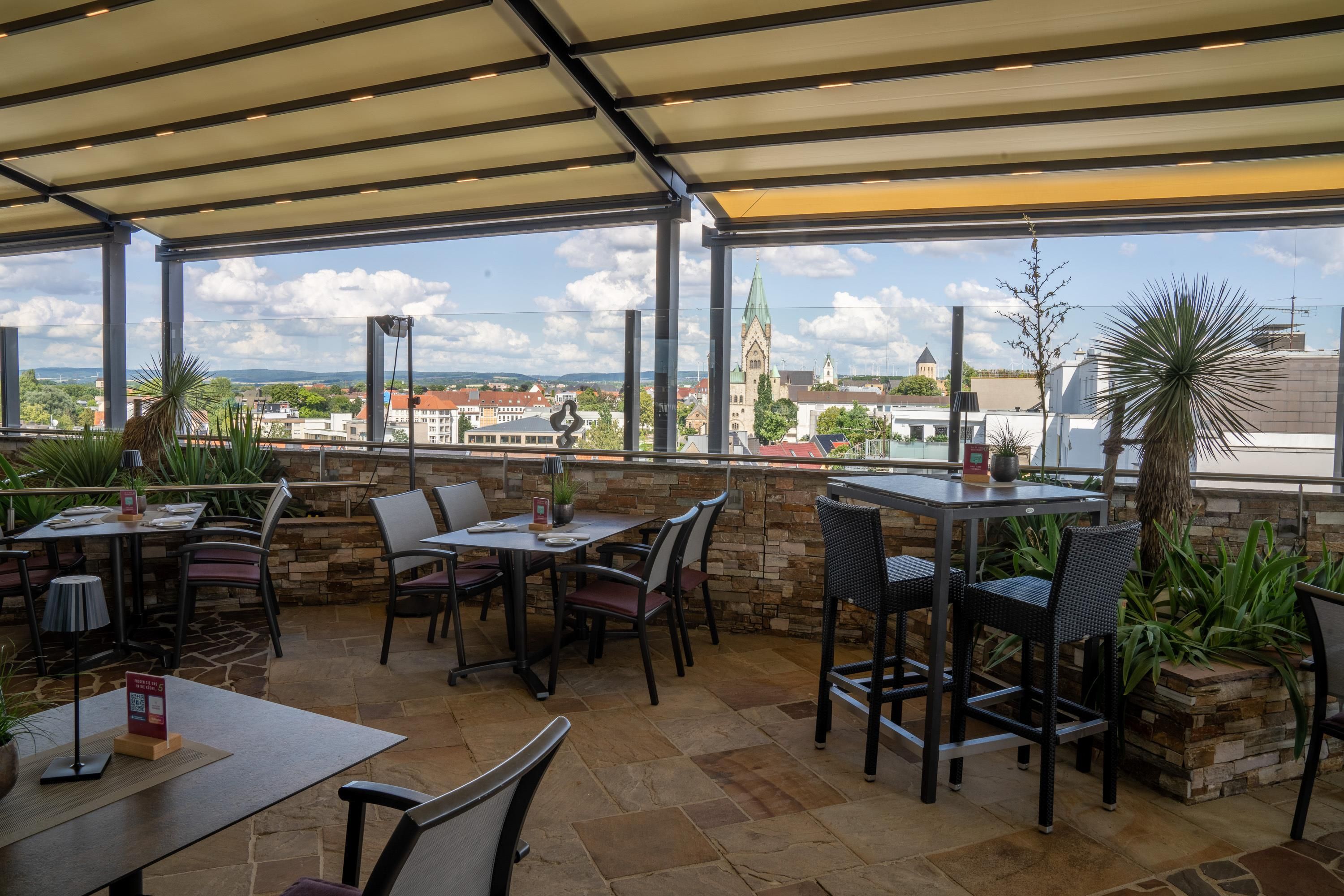 An outdoor patio with stone flooring and metal tables and chairs.