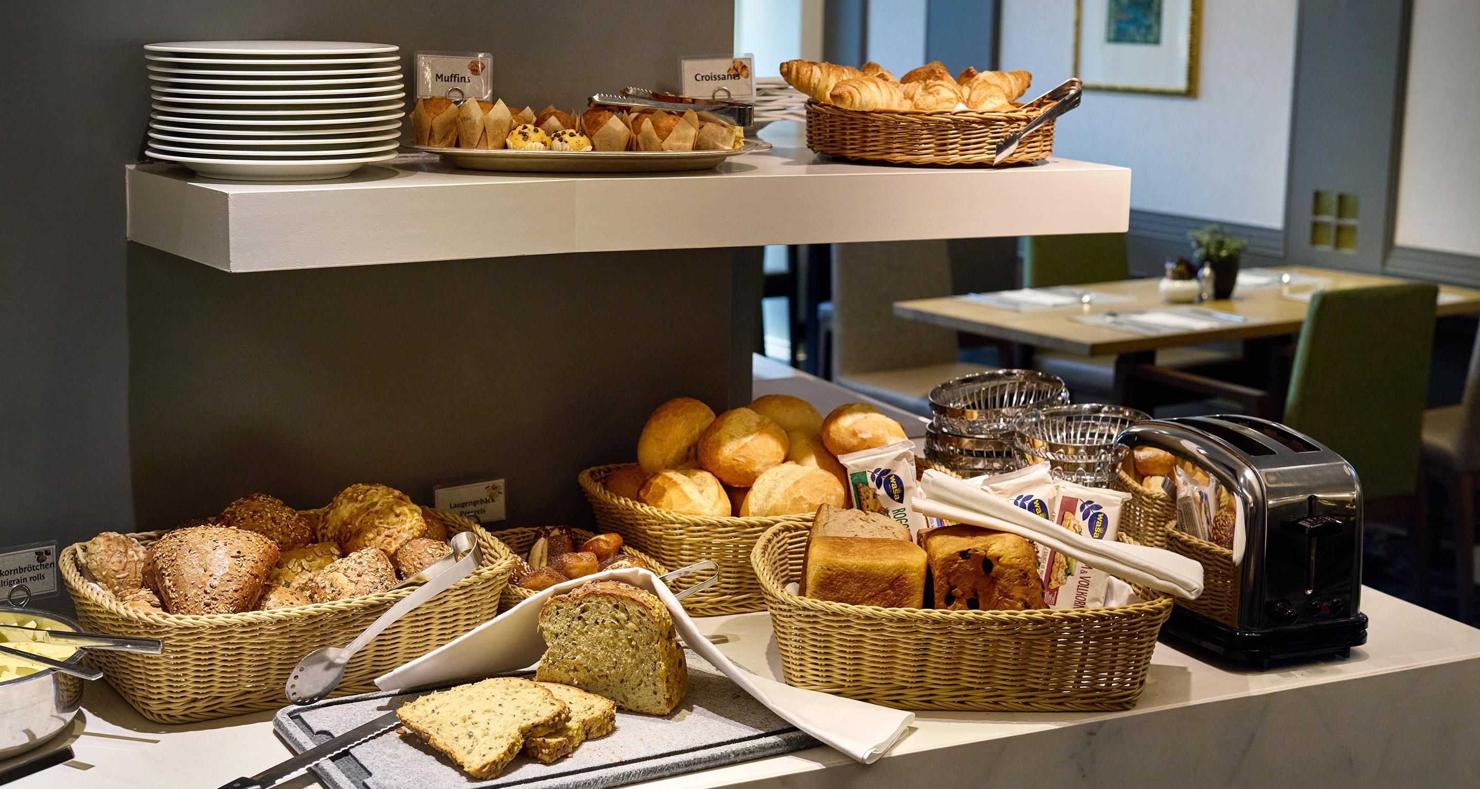 A buffet with various breads, muffins, and croissants.