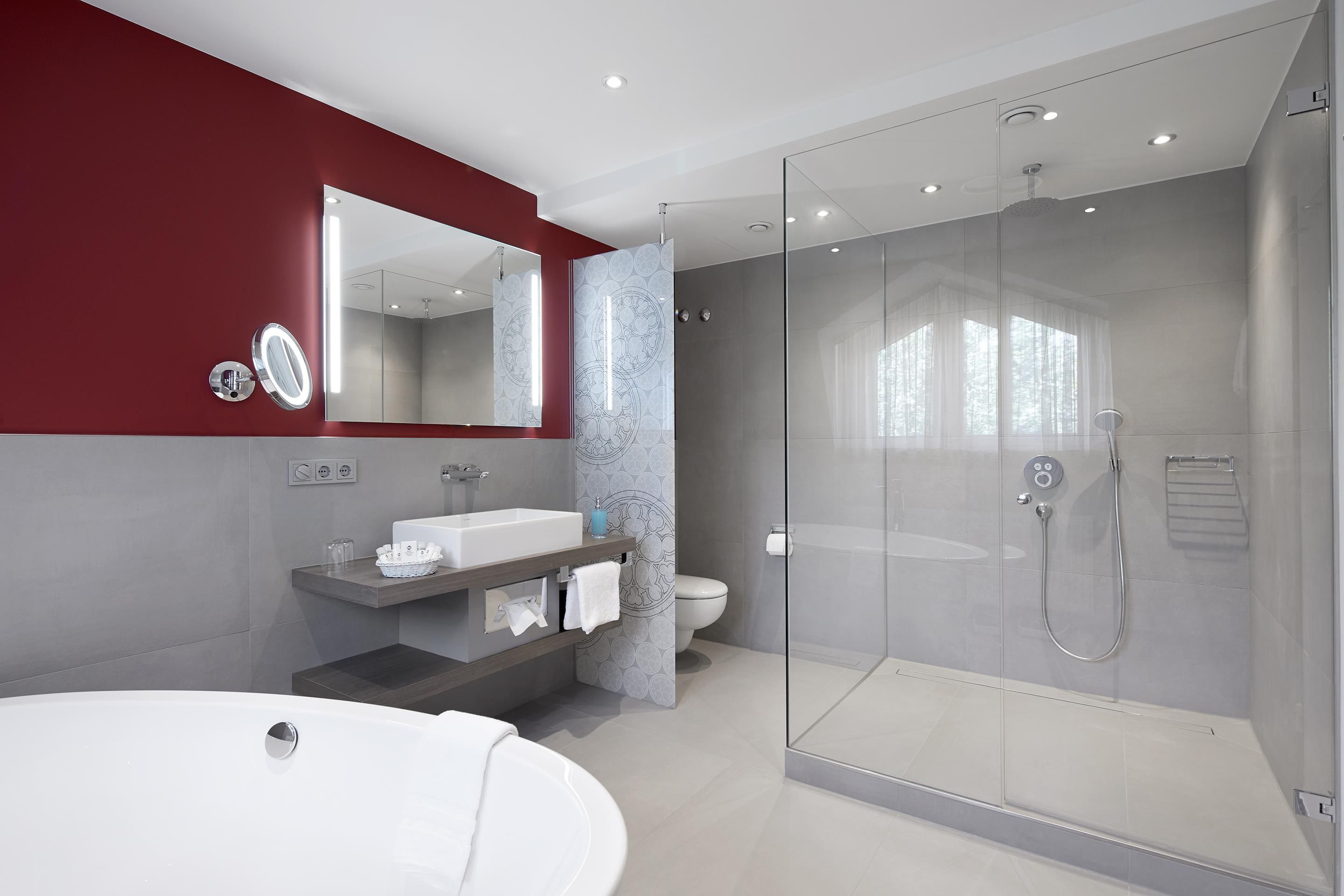 A modern bathroom with a glass-enclosed shower, a large mirror, and a vanity with a sink and towel rack.