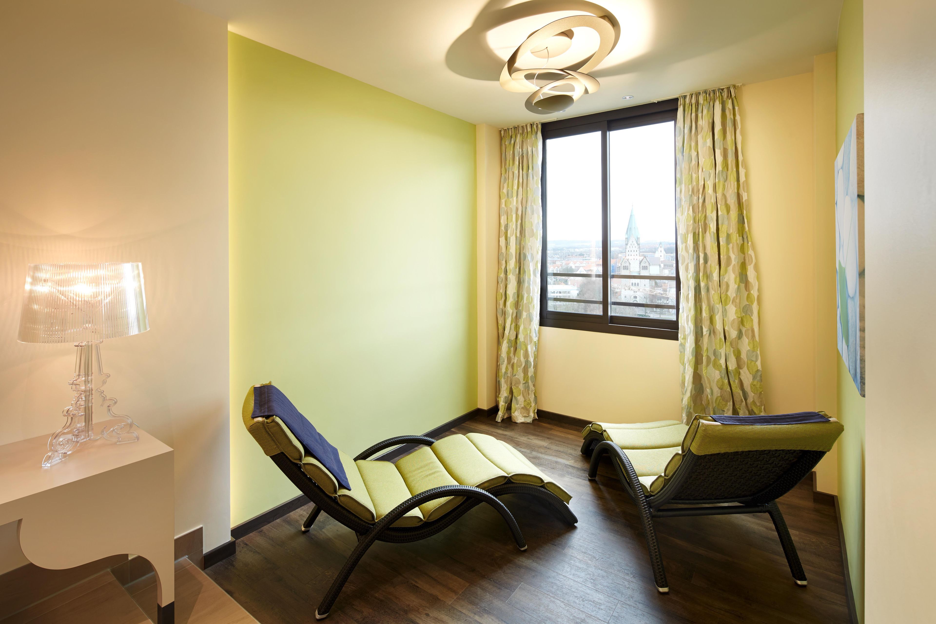 A room with two reclining chairs, a lamp, and a window with curtains.