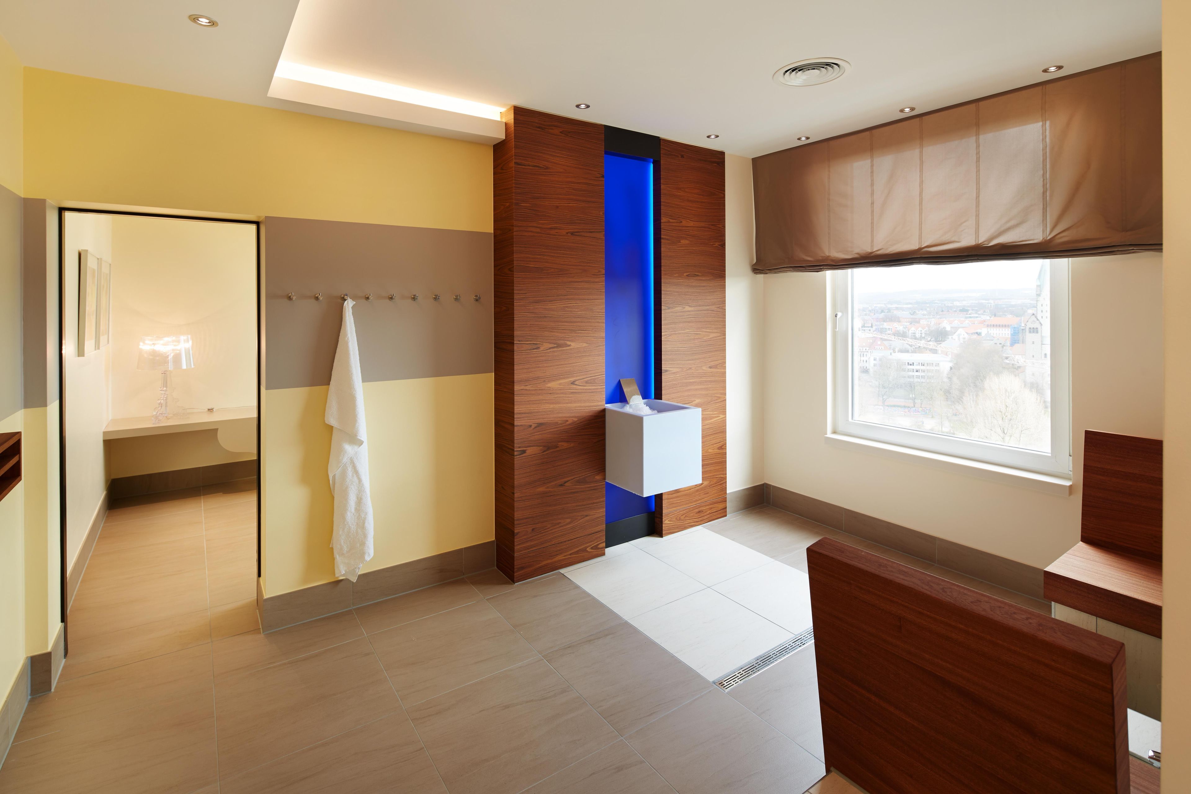 A modern bathroom with a shower, a towel rack, a window with a view, and a wooden accent wall.