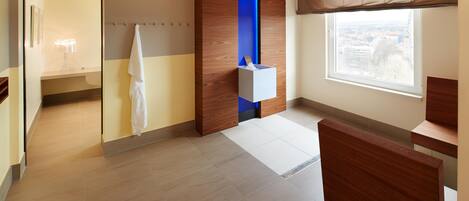 A modern bathroom with a shower, a towel rack, a window with a view, and a wooden accent wall.
