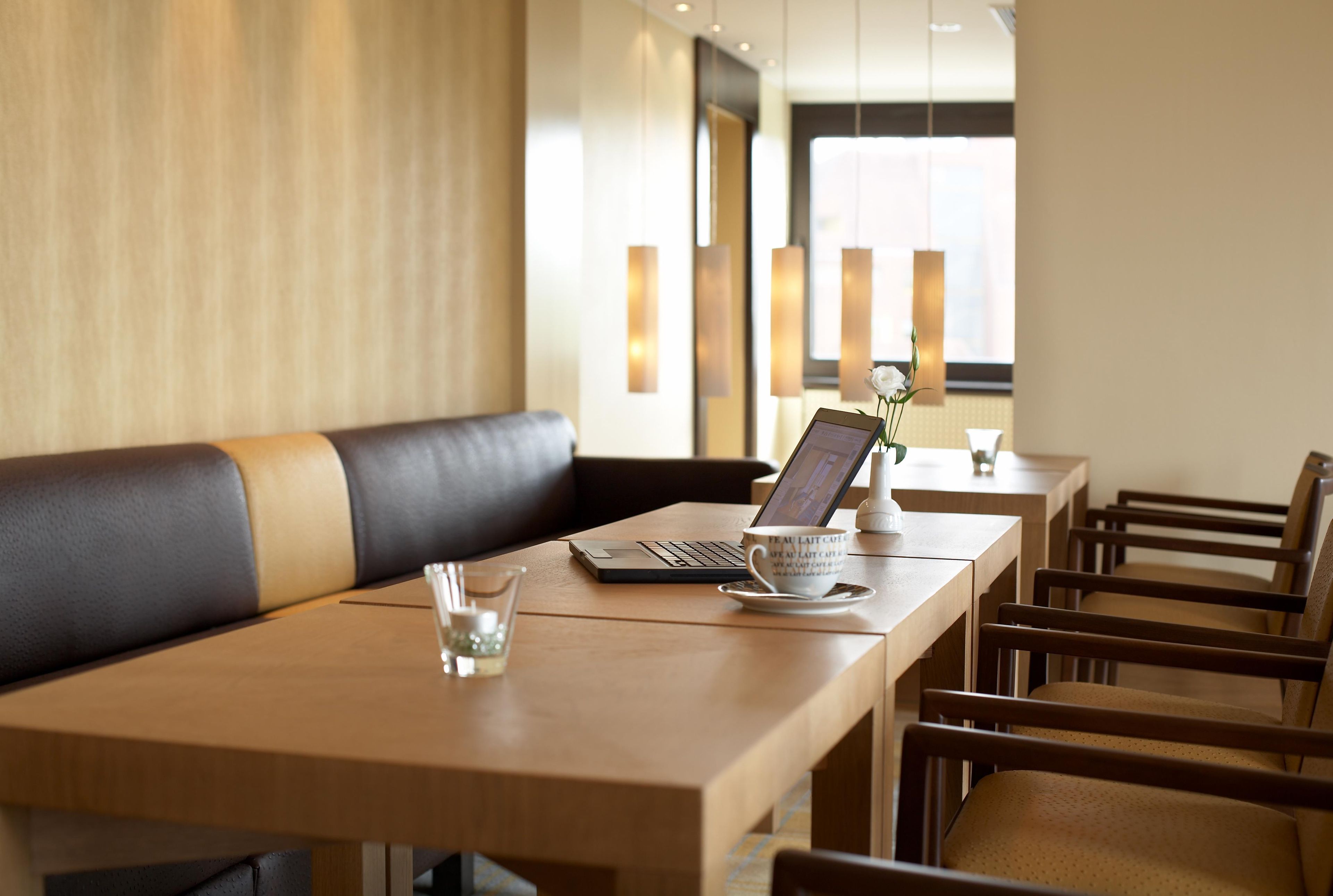 Ein moderner Essbereich mit einem Holztisch, einem Laptop, einer Tasse und einer Vase mit einer Blume.
