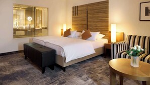 A hotel room with a bed, a small table, a chair, a bench, and a wall-mounted mirror. - Best Western Plus Arosa Hotel (Paderborn)