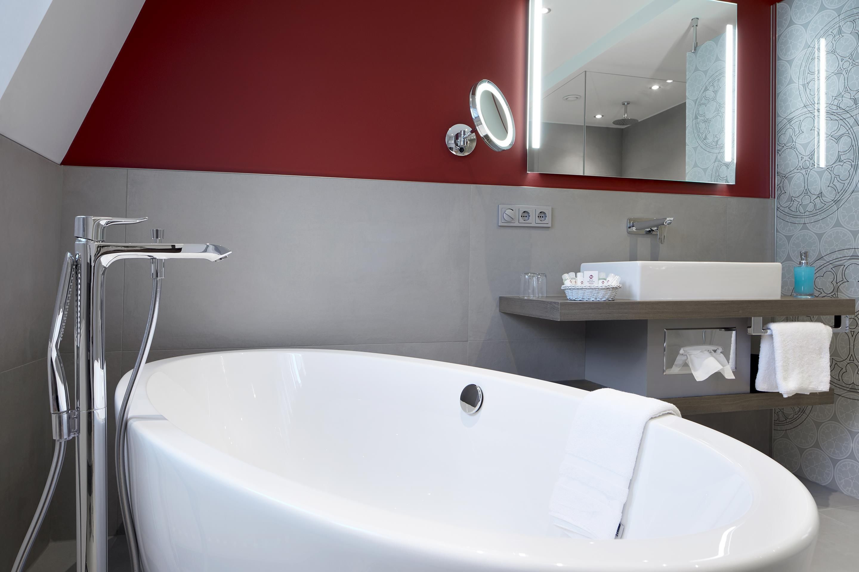A modern bathroom with a freestanding bathtub, a vanity with a mirror, and a towel rack.