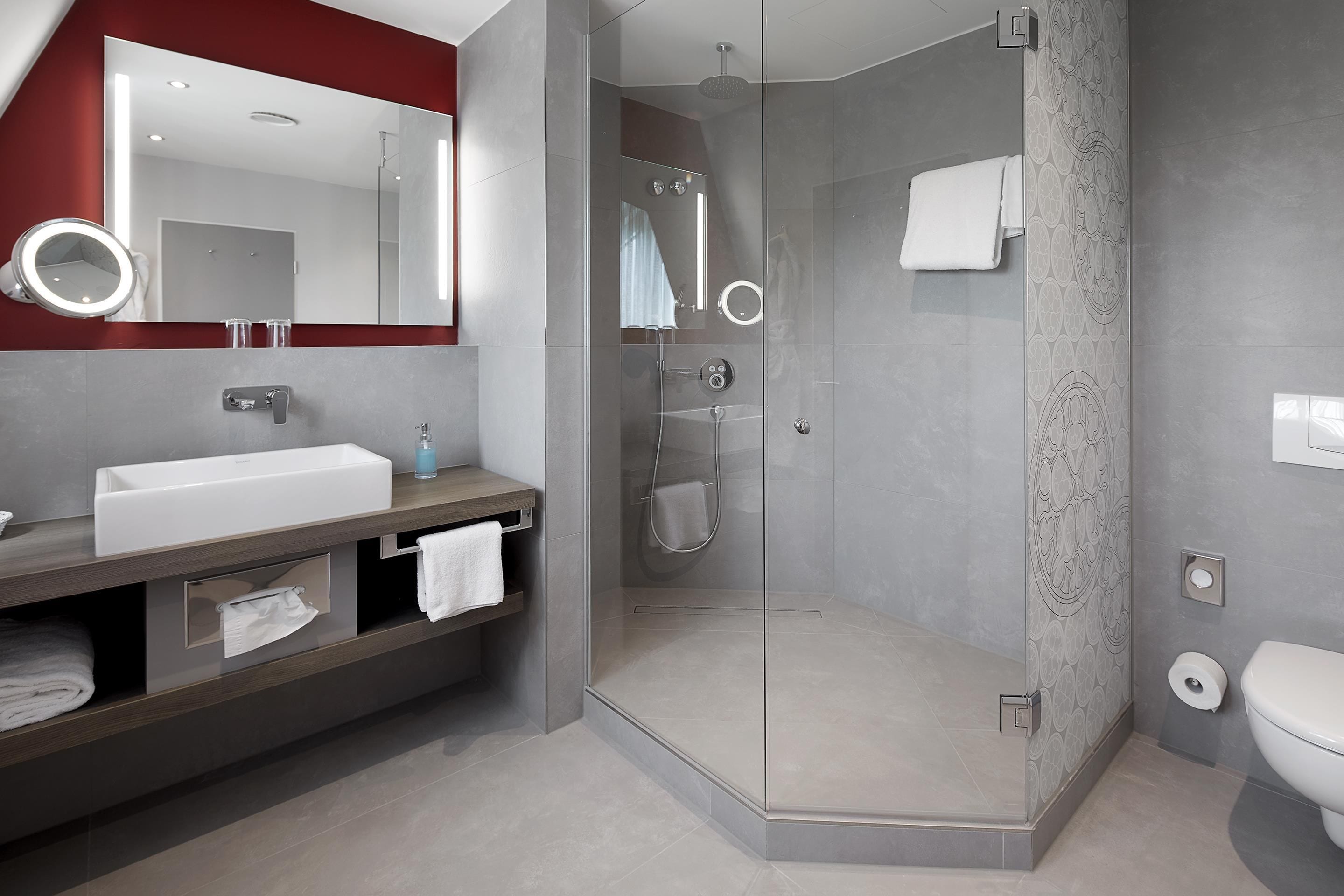 A modern bathroom with a glass-enclosed shower, a white sink, and a vanity with a mirror.