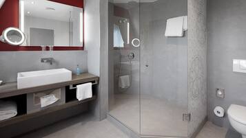 A modern bathroom with a glass-enclosed shower, a white sink, and a vanity with a mirror.