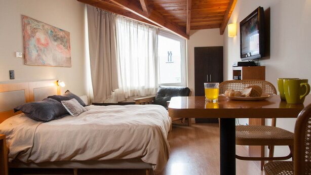 Una habitació acollidora amb un llit, una taula amb articles per a l'esmorzar, un televisor i un quadre a la paret.
